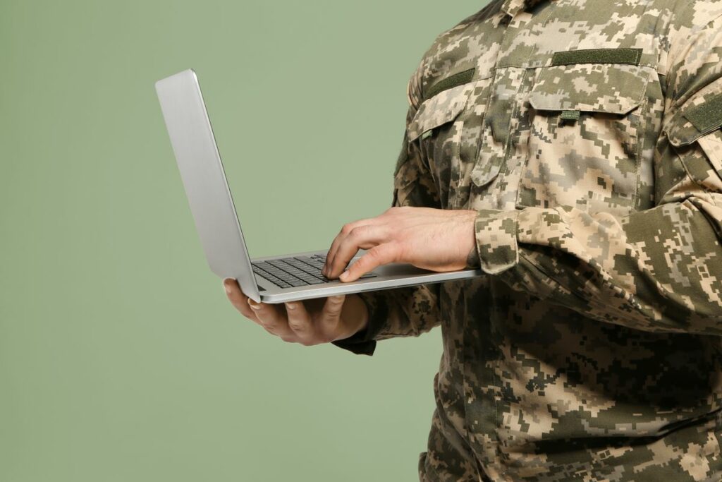 Soldier with laptop on grey background, closeup