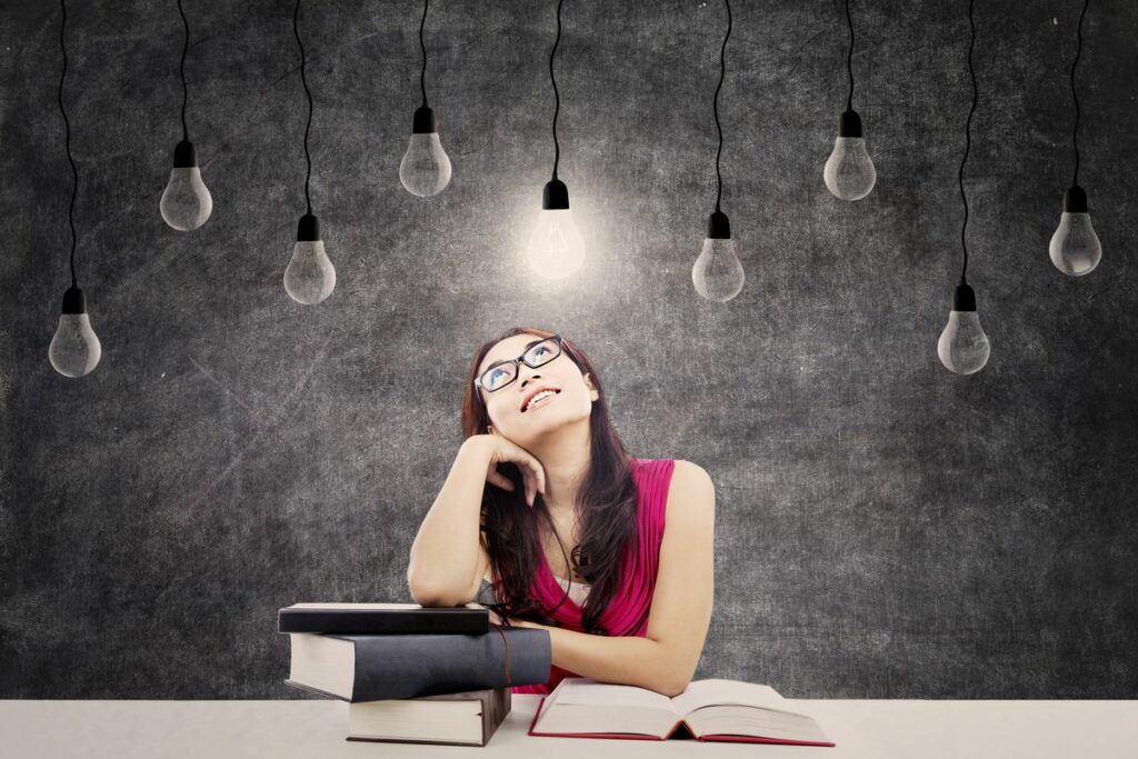 Portrait of smart female college student with books and bright light bulb above her head as a symbol of bright ideas